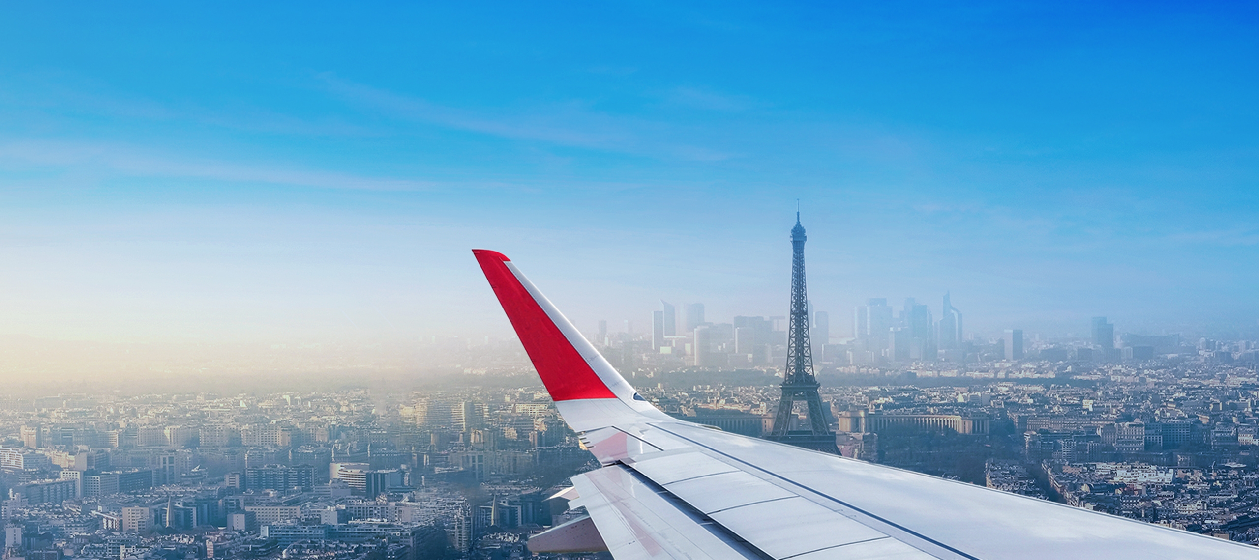 Sicht aus einer Flugzeugkabine in der Luft: Flugzeugflügel und Blick auf Paris mit dem Eifelturm.