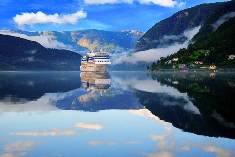 Kreuzfahrtschiff im norwegischen Fjord bei Ulvik, umgeben von Bergen, Wolken und ruhigem Wasser
