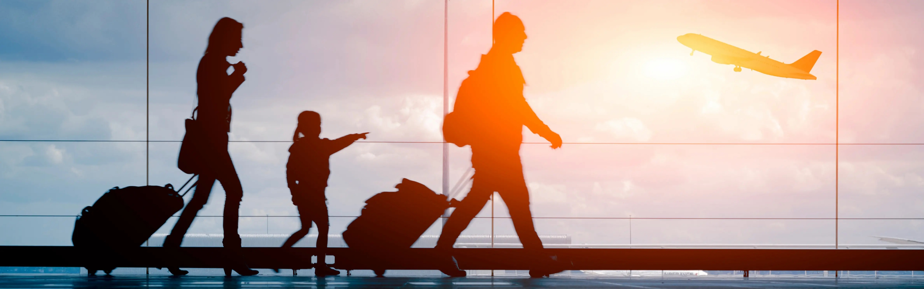 Blick von Innen auf eine Glasfront eines Flughafens; die Sonne strahlt herein, ein Flugzeug hebt ab; vor der Glasfront läuft eine dreiköpfige Familie mit Koffern, aufgrund der Lichteinstrahlung sieht man aber nur ihre Umrisse.