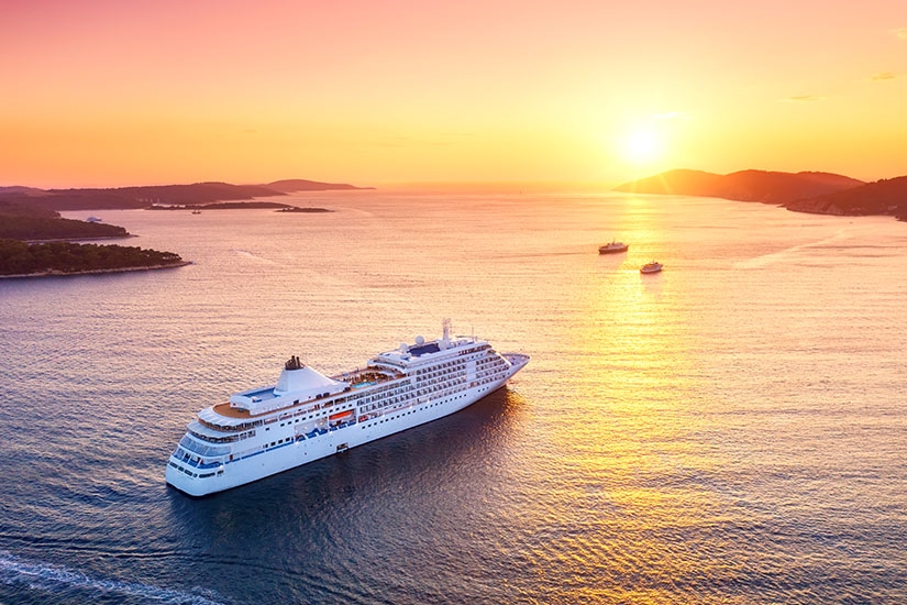Kreuzfahrtschiff fährt entlang der kroatischen Küste im goldenen Licht des Sonnenuntergangs