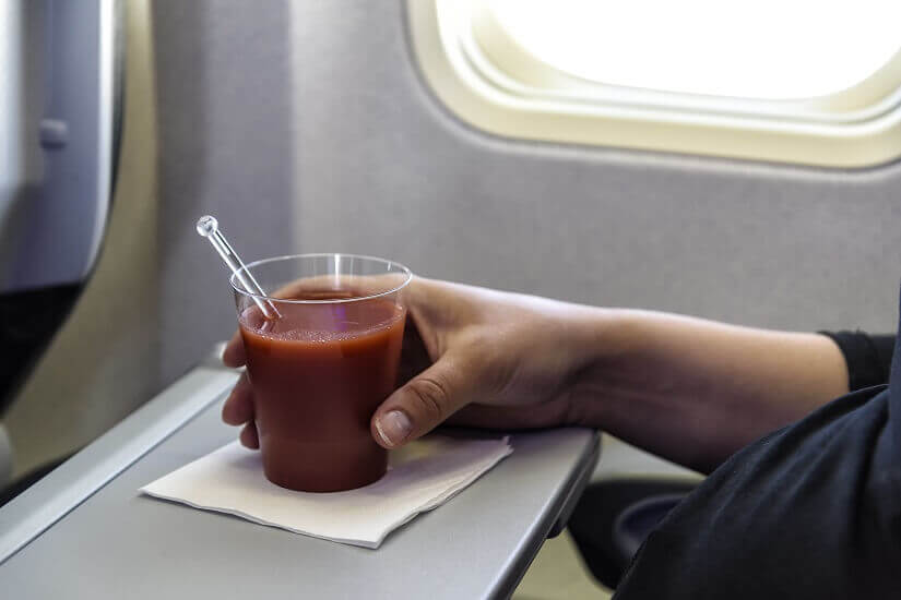 Ein Passagier trinkt Tomatensaft im Flugzeug