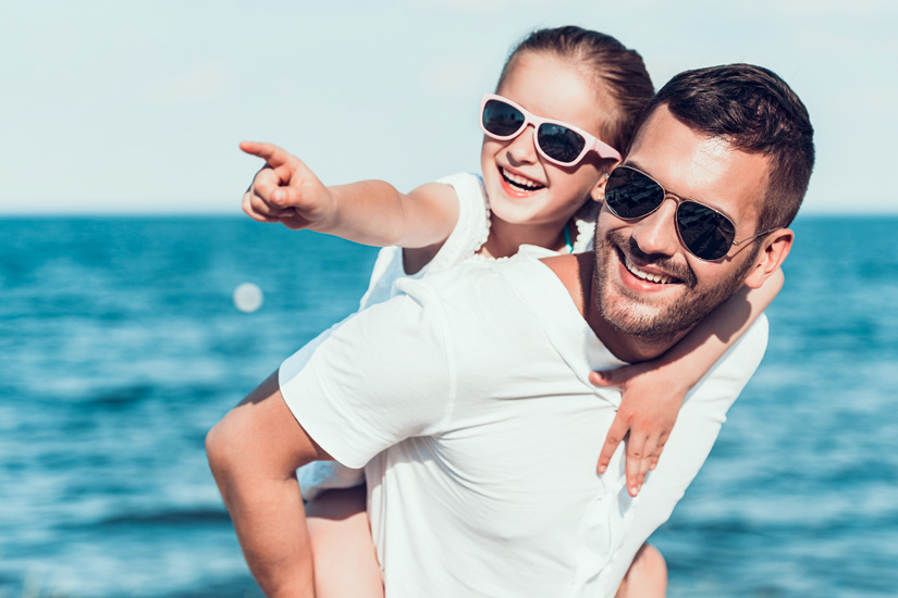 Vater und Tochter mit Sonnenbrillen am Meer