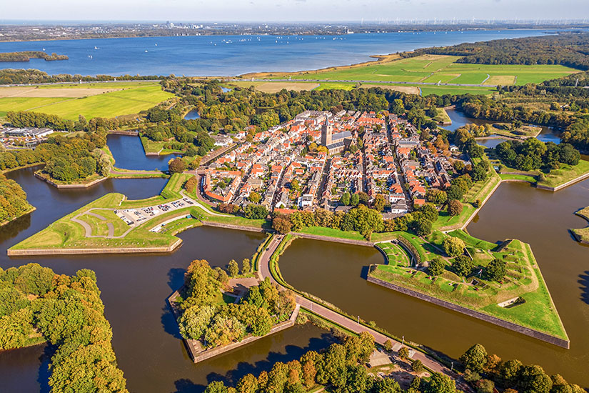 Blick von oben auf eine Stadt, die von einer sternförmigen Festung und Wasser umgeben ist. Holland Naarden