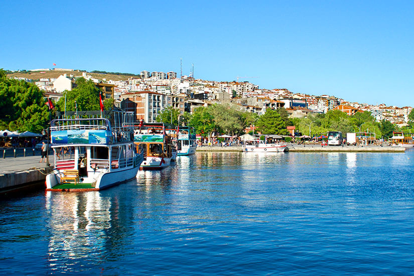 Hafenpromenade mit kleinen Booten. Im Hintergrund ist die Stadt zu sehen. Sinop Sommer