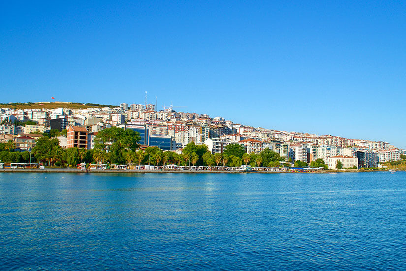 Blick auf eine Küstenstadt, davor blaues Wasser. Sinop Stadt
