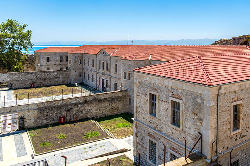 Gefängnis aus Stein mit einem roten Dach, im Hintergrund ist das Meer zu sehen. Sinop Gefaengnis