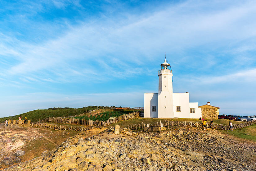 Weißer Leuchtturm in einer Felsenlandschaft unter blauem Himmel. Tuerkei Leuchtturm