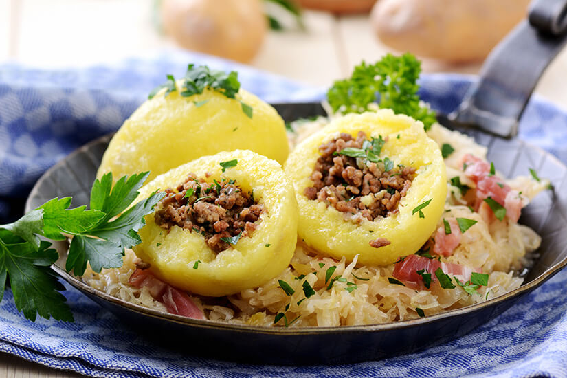 Mit Speck gefüllte Knödel auf Sauerkraut in einer Pfanne serviert. Ried im Innkreis Knoedel