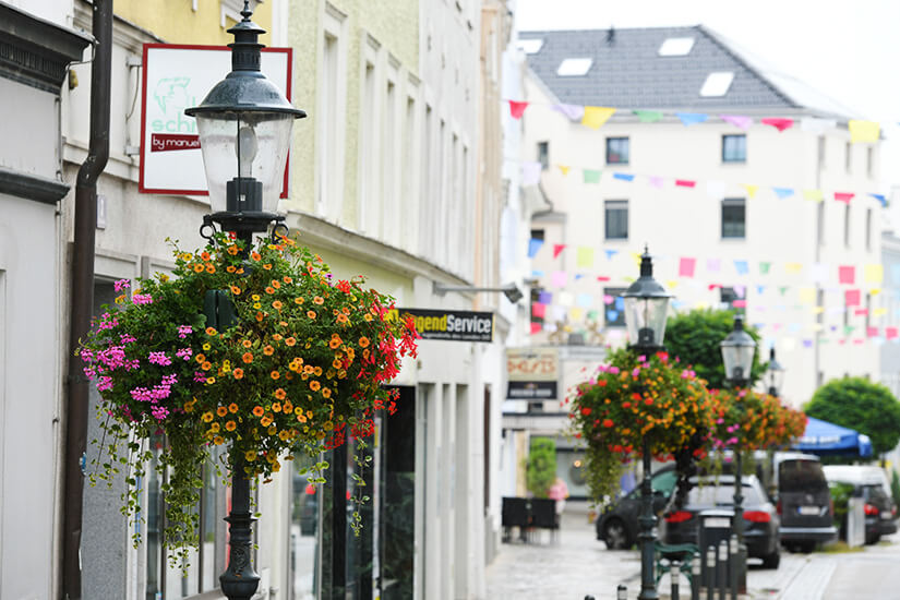 Straßenlaterne mit Blumen, im Hintergrund sind Häuserfassaden zu sehen. Ried im Innkreis Stadt