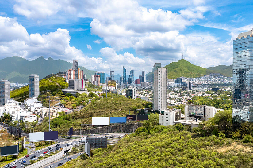 Die Stadt Monterrey in Mexiko vor einem blauen Himmel mit prächtigen Wolken. Die Skyline und Grünanlagen sind zu sehen. Monterrey Mexiko Anreise