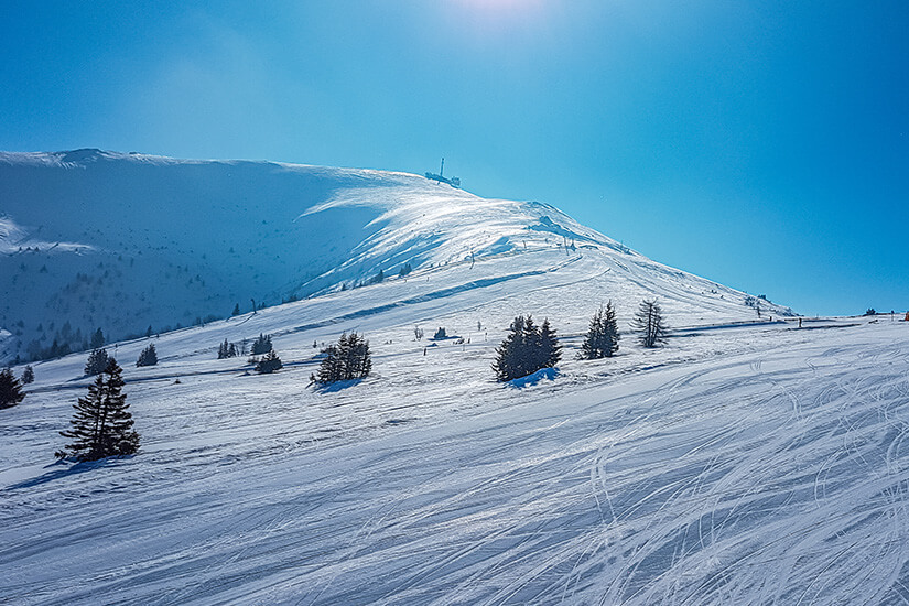 Winterlich verschneites Skigebiet unter strahlend blauem Himmel. Wolfsberg Skigebiet