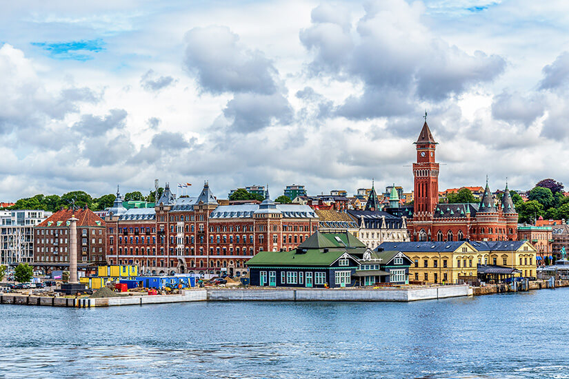 Die Stadt Helsingborg vom Öresund aus betrachtet. Gebäude in verschiedenen Farben liegen an der Meerenge. Helsingor Daenemark Helsinborg
