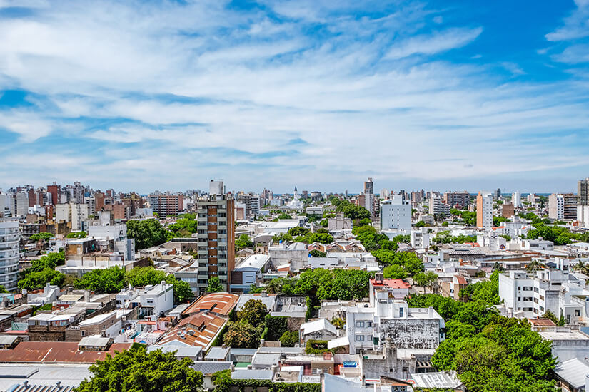 Die Stadt Rosario mit hellen Gebäuden und grünen Blätterdächern dazwischen ist zu sehen. Rosario Argentinien Willkommen
