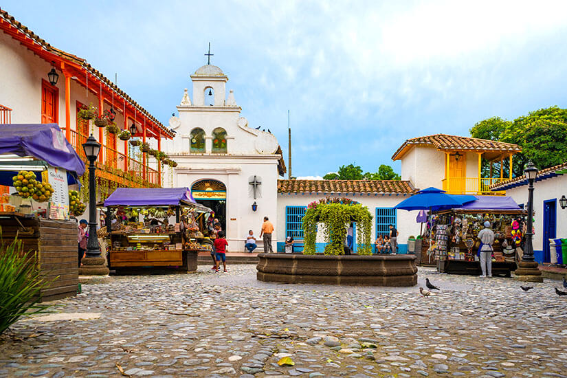 Der zentrale Platz des Pueblito Paisa in Medellín mit einer kleinen weißen Kirche und Marktständen Medellín Kolumbien Pueblito Paisa