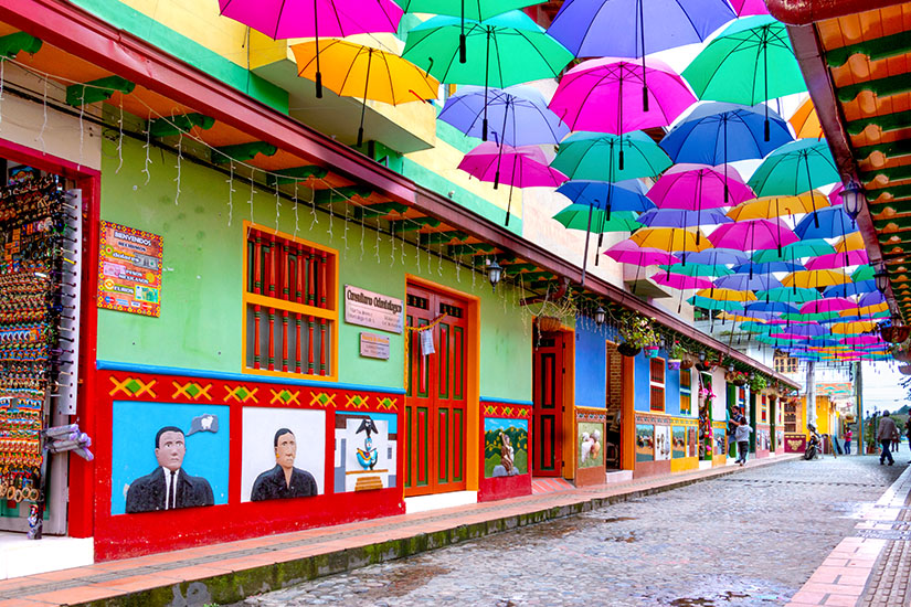 Bunte Straße in Guatapé mit dekorativen Regenschirmen und bemalten Hausfassaden. Medellín Kolumbien Guatapé