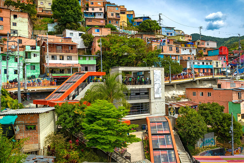Orangefarbene Freiluft-Rolltreppen (Escaleras Eléctricas) in einem bunten Hangviertel von Medellín. Medellín Kolumbien Hügelsicht mit Rolltreppen
