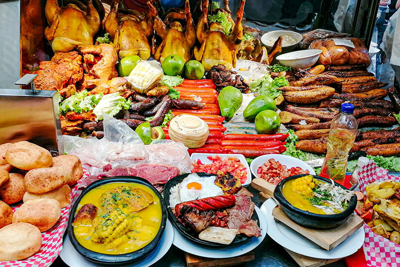Marktstand in Medellín mit einer Auswahl an traditionellen kolumbianischen Gerichten wie Bandeja Paisa und gebratenem Huhn. Medellín Kolumbien Marktstand mit Essen