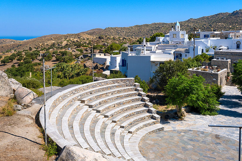 Das Amphitheater von Volax liegt eingebettet in die Landschaft. Direkt daneben schmiegen sich Häuser an den Hang, während eine Kirche das Bild prägt. Tinos Griechenland Volax