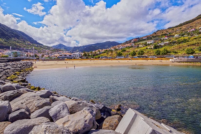 Strandabschnitt in Machico. Der Praia de Machico ist ein Sandstrand in der Bucht. Im Hintergund ist die Stadt sichtbar. Machico Portugal Strandabschnitt