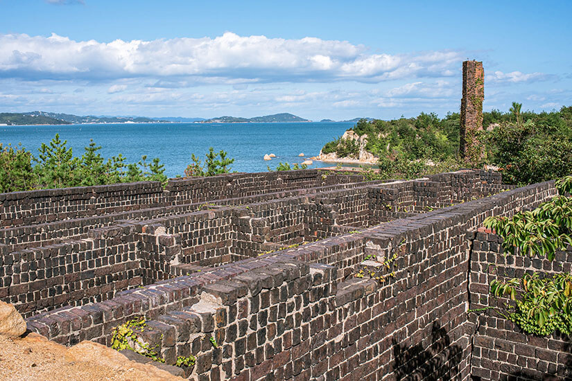 Die Ruinen einer ehemaligen Produktionsstätte fügt sich in die grüne Insellandschaft mit Meer im Hintergrund ein. Naoshima Japan Inujima