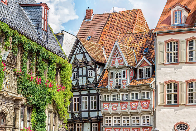 Fachwerkhäuser mit reich verzierten Fassaden und steilen Ziegeldächern stehen dicht an dicht. Begrünte Mauern, Blumen und geschnitzte Details verleihen der Szene einen sehr historischen, gepflegten Eindruck. Quedlinburg Altstadt