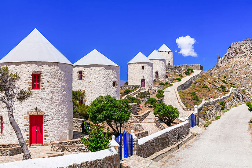 Fünf Weiße Windmühlen mit roten Türen und Fenstern entlang des Hügels. Leros Griechenland Windmuhlen