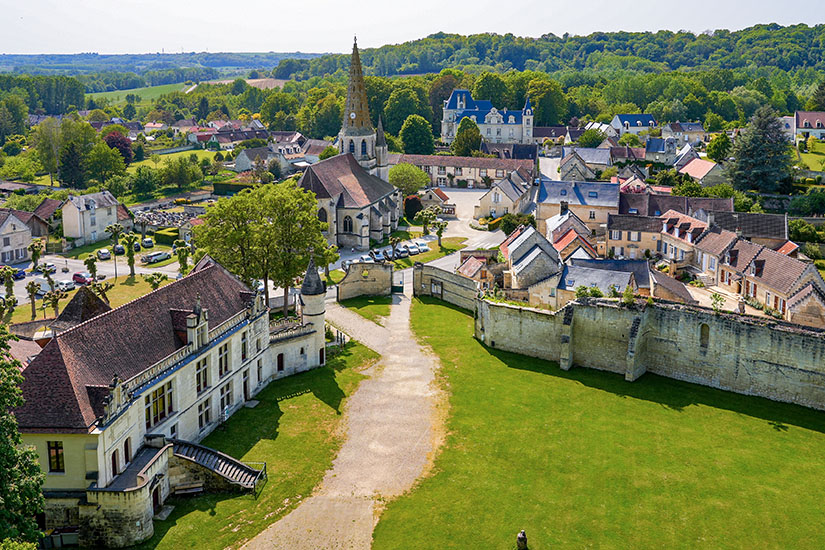 Eine Grünanlage mit Häusern, Stadtmauer und Kirchturm aus der Vogelperspektive im Département Aisne ist zu sehen. Picardie Frankreich Willkommen