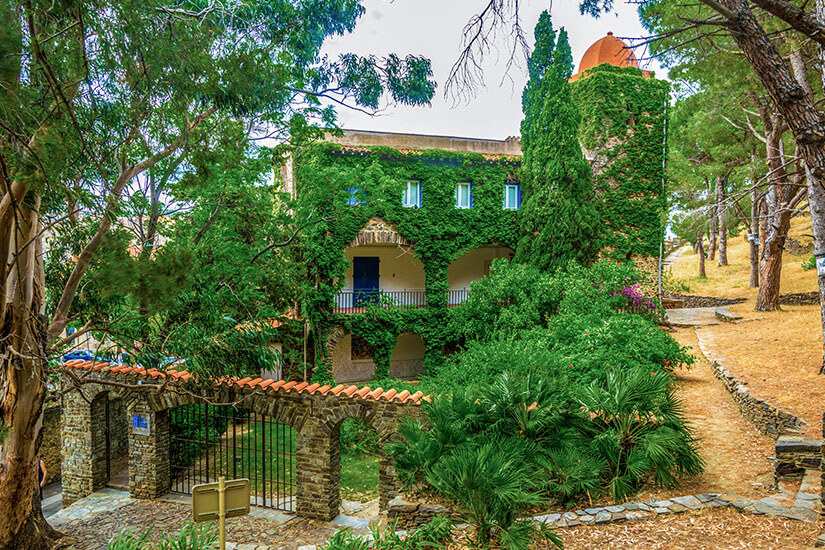 Das üppig mit Efeu bewachsene Musée d’Art Moderne in Collioure, ein historisches Stadtpalais mit Arkaden und einem Türmchen, eingebettet in einen mediterranen Park mit Pinien und Zypressen. Collioure Frankreich Musée d'Art Moderne