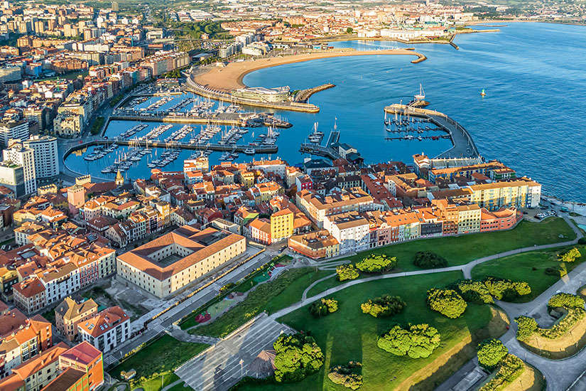 Aus der Vogelperspektive offenbart Gijón seine ganze Schönheit: ein kompakter Yachthafen, ein geschwungener Sandstrand und die roten Ziegeldächer der Altstadt, die sich an die Küste schmiegen. Grüne Parkanlagen rahmen die Stadt ein und erinnern daran, dass dies das grüne Spanien ist. Städte Spanien Gijon