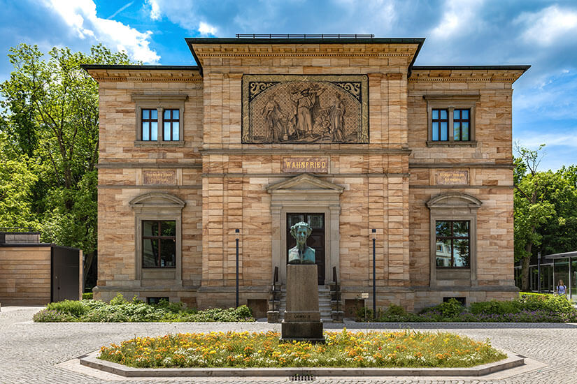 Die repräsentative Villa Wahnfried mit ihrer klassizistischen Fassade und dem kunstvollen Fries war ab 1874 Richard Wagners Wohnhaus. Heute beherbergt sie das Richard-Wagner-Museum und ist ein Pflichtbesuch für Kulturinteressierte. Die Bronzebüste vor dem Eingang erinnert an den berühmten Bewohner. Bayreuth Deutschland Wahnfried Villa