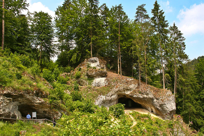 Eine eindrucksvolle Höhlenöffnung im Kalkfelsen, umgeben von dichtem Grün, lädt zur Erkundung ein. Die Fränkische Schweiz nahe Bayreuth ist für ihre zahlreichen Tropfsteinhöhlen bekannt. Hier taucht ihr in eine unterirdische Welt ein, die Jahrmillionen alt ist. Bayreuth Deutschland Teufelshoehle