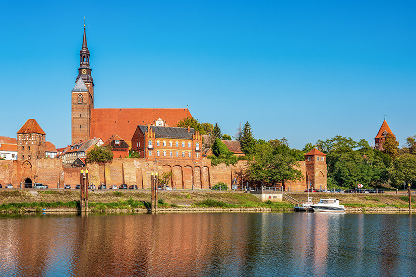 Ein Blick über die Elbe auf die Altstadt von Tangermünde mit roten Gebäuden und der Stephanskirche. Tangermuende Deutschland Radweg