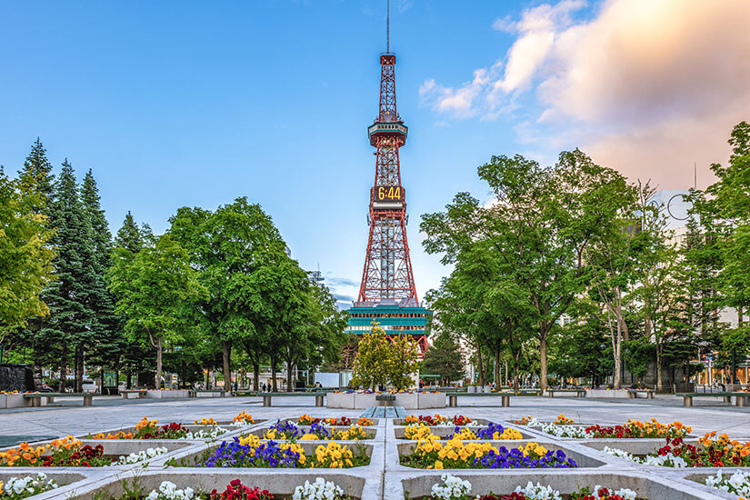Der ikonische Fernsehturm von Sapporo erhebt sich über den üppig begrünten Ōdori-Park. Bunte Blumenbeete und schattige Baumreihen verleihen dem Zentrum der nördlichsten Millionenstadt Japans eine sommerliche Leichtigkeit. Städte Japan Sapporo