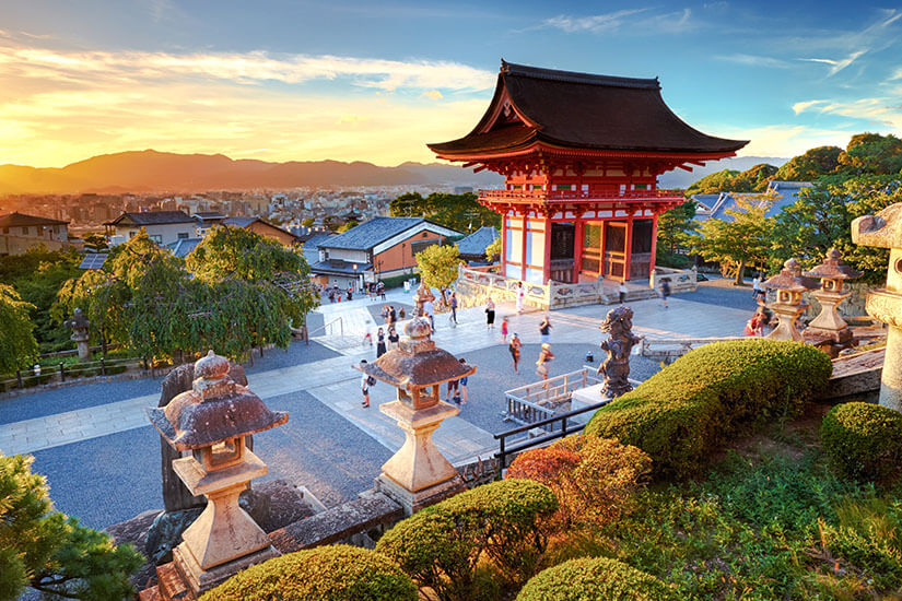 Der Kiyomizu-dera bei Sonnenuntergang, einer der berühmtesten Tempel Kyōtos. Die rot-orangefarbene Pagode überblickt die Dächer der alten Kaiserstadt, während das warme Abendlicht die Steinlaternen und gepflegten Gärten in goldene Töne taucht. Städte Japan Kyoto