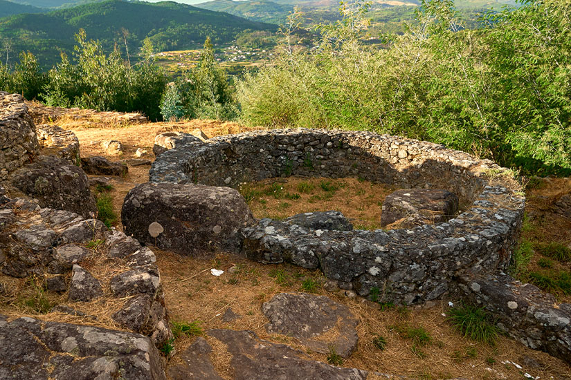 Überreste kreisförmiger Steinmauern einer antiken keltischen Siedlung auf einem Hügel mit weitem Blick über das grüne Tal und ferne Berge. Guimaraes Portugal Keltische Siedlung