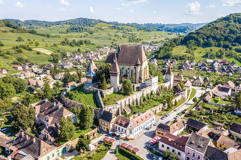Die Wehrkirche thront im Dorf Biertan in Rumänien. Häuser und viel Grün umgeben das Bauwerk. Sighisoara Rumaenien Biertan