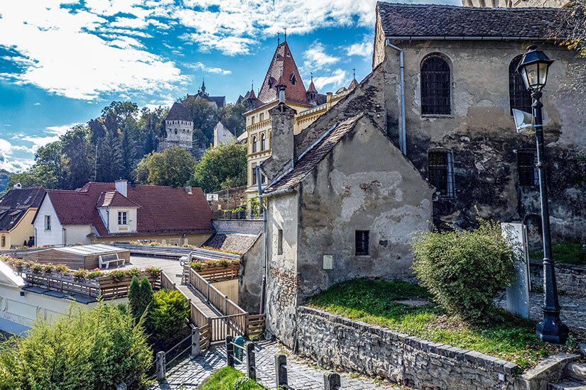 Eine Straße führt vorbei an Häusern und historischen Bauwerken in der Stadt Schässburg. Sighisoara Rumaenien Strasse