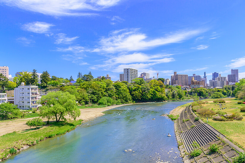 Der Hirose-Fluss schlängelt sich ruhig durch Sendai und verbindet Natur und Stadt auf harmonische Weise. Grüne Ufer und Bäume rahmen das Wasser ein, während im Hintergrund die Skyline der Stadt aufragt. Der Fluss ist ein beliebter Ort zum Spazieren und Entspannen für Einheimische und Besucher. Sendai Japan Fluss