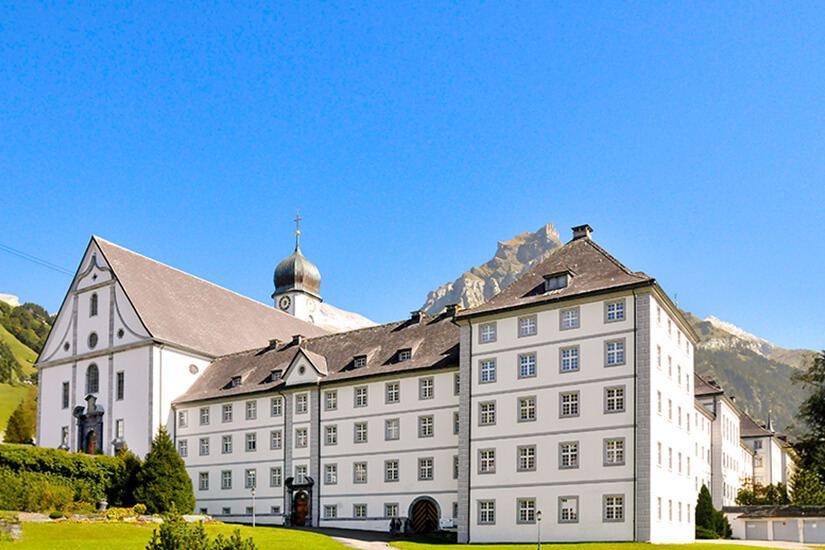 Das Kloster Engelberg mit seiner weißen Fassade thront im Grünen. Engelberg Schweiz Kloster