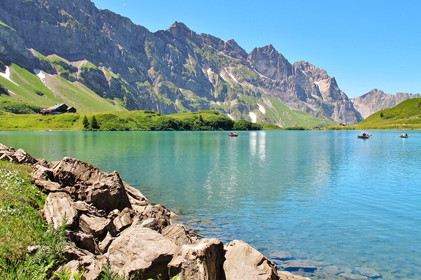 Der Trübsee bei Engelberg vom Ufer aus betrachtet. Das Wasser leuchtet inmitten der alpinen Umgebung in Blau- und Türkistönen. Engelberg Schweiz See