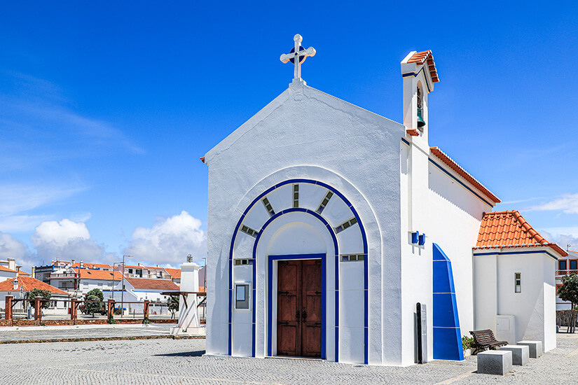 Eine weiße Kapelle mit blauen Verzierungen und rotem Dach ist zu sehen. Fischerweg Portugal Kapelle