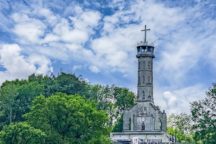 Der Turm Wilhelminatoren thront umgeben von Grün vor blauem Himmel. Valkenburg Niederlande Turm