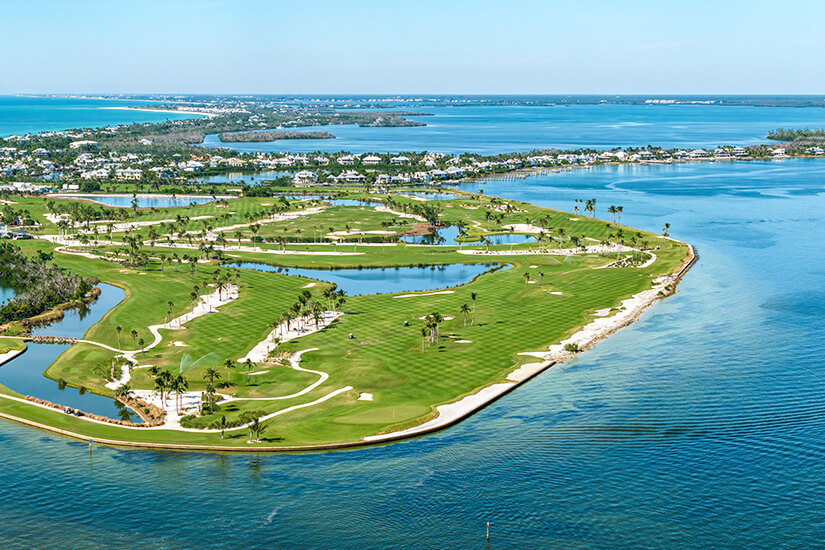 Ein spektakulärer Inselplatz erstreckt sich als grüne Halbinsel ins türkisblaue Wasser, gesäumt von Palmen und weißen Sandbunkern. Die Luftaufnahme zeigt, wie eng Fairways und Ozean hier verschmelzen. Jeder Fehlschlag könnte im Wasser landen, was diesen Kurs so reizvoll wie anspruchsvoll macht. Golfdestinationen weltweit USA