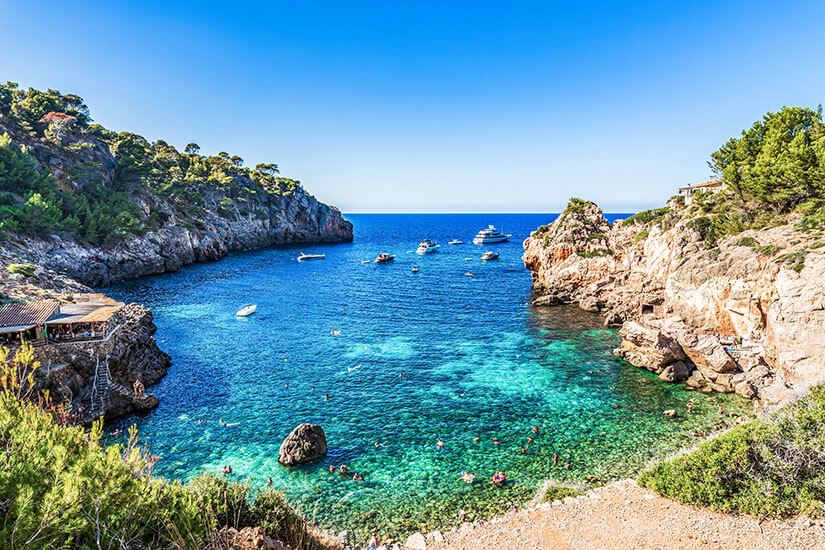 Eine malerische Bucht mit klarem Wasser in Blau- und Türkisfarben ist zusehen. Deia Spanien Cala