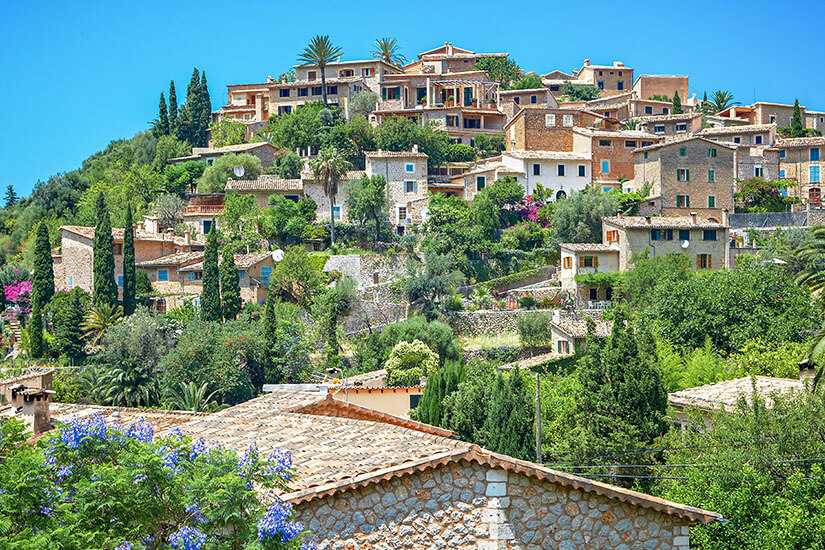 Das Bergdorf Deià ist zu sehen und erhebt sich mit seinen leuchtenden Steinfassaden zwischen der Natur hervor. Deia Spanien Wetter