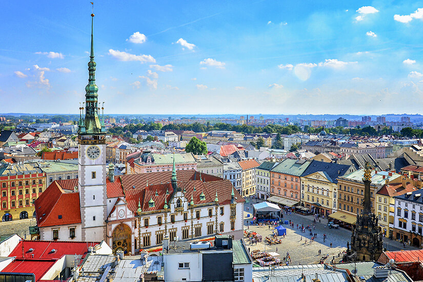 Der Obere Ring bildet das pulsierende Herz der Altstadt mit dem prächtigen Rathaus und seinem 75 Meter hohen Turm. Rechts ist die Dreifaltigkeitssäule zu sehen, die zum UNESCO-Weltkulturerbe zählt. Bunte Bürgerhäuser verleihen dem Platz seinen einzigartigen Charme. Olomouc Tschechien Rathaus