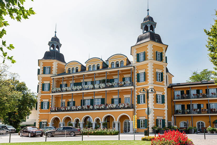 Das schöne Schloss Velden mit seiner gelben Fassade und grünen Jalou Velden Oesterreich Schloss