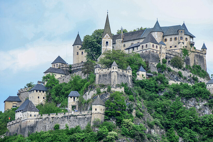 Ein Blick auf Burg Hochosterwitz. Die Anlage thront auf einem grün bewachsenen Hügel. Velden Oesterreich Burg