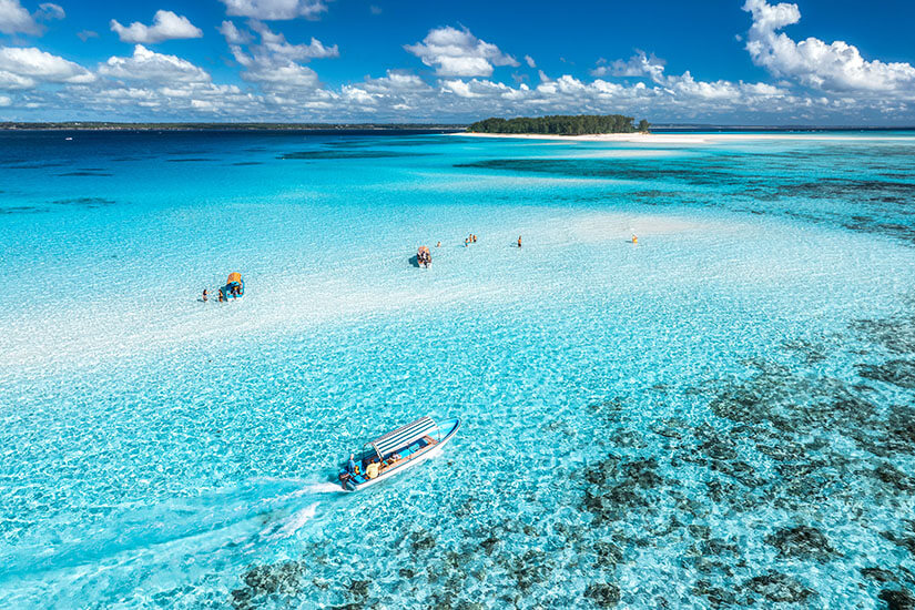Mnemba Island ist eine kleine private Insel vor der Nordostküste Sansibars und das beliebteste Schnorchel- und Tauchziel der Region. Das Wasser schimmert in unzähligen Blau- und Türkistönen und ist so klar, dass der sandige Grund deutlich sichtbar wird. Kleine Boote bringen Besucher zu den Schnorchelspots rund um das Atoll. Sansibar Strände Mnemba Island