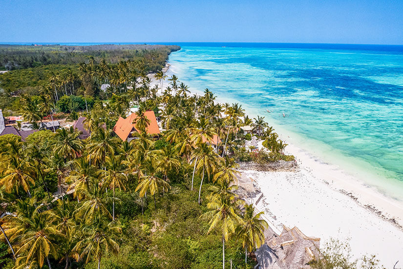 Kiwengwa erstreckt sich entlang der Nordostküste Sansibars und gilt als einer der längsten Strände der Insel. Dichte Palmenwälder und vereinzelt orange leuchtende Dächer der Resorts fügen sich harmonisch in die tropische Landschaft ein. Das vorgelagerte Riff schützt die Bucht und schafft ein leuchtend türkisfarbenes Wasser, ideal zum Entspannen. Sansibar Strände Kiwengwa Beach